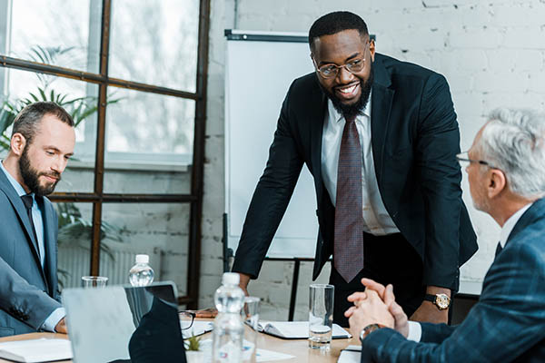 selective focus of cheerful african american business coach smiling near coworkers cheerful business coach business training seminars